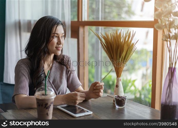 woman thinking and using tablet in the cafe