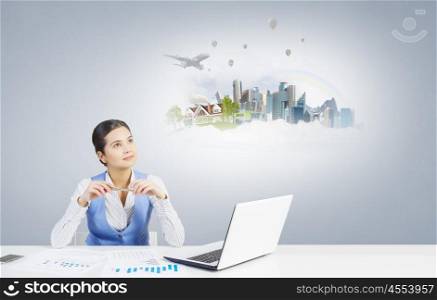 Woman thinking over her project. Beautiful woman sitting at table with laptop and dreaming