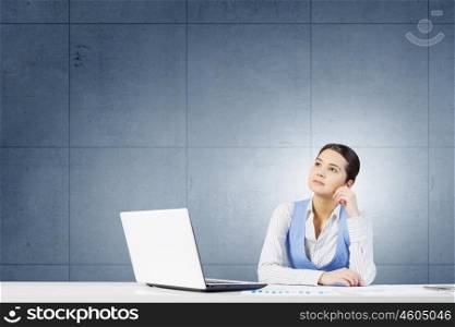 Woman thinking over her project. Young attractive businesswoman sitting at table and thinking something over