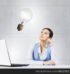 Woman thinking over her project. Young attractive businesswoman sitting at table and thinking something over