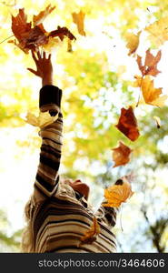 Woman throwing autumn leaves in the air