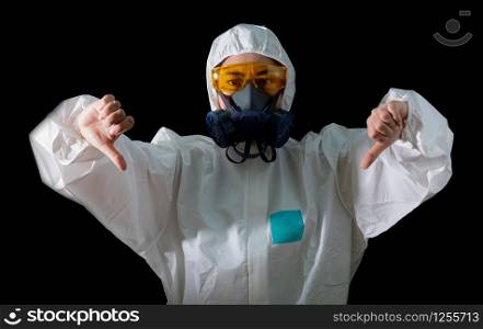 Woman thumb down sign in a chemical protective clothing and antigas mask with yellow glasses at black background, Women scientist in safety suit, Safety virus infection concept