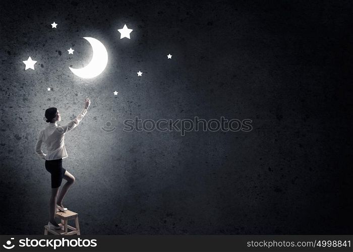 Woman touch the moon. Young woman standing on chair and reaching moon