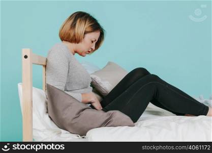 woman touching hurting belly bed