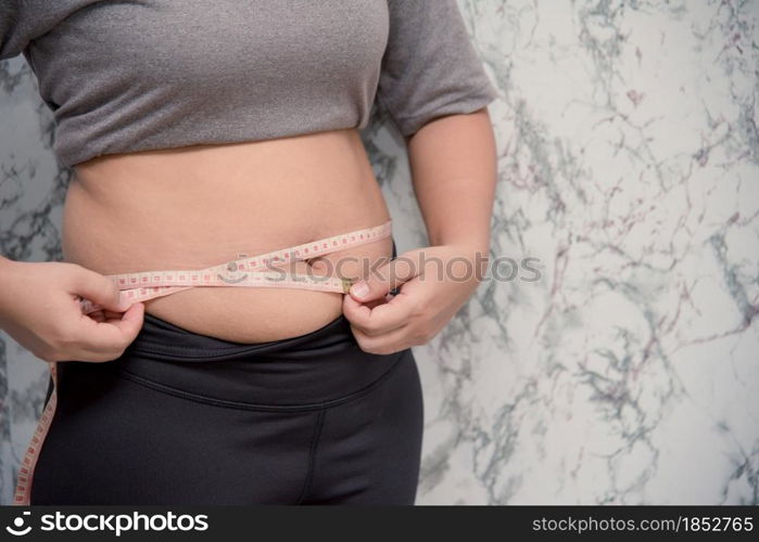 Woman touching stomach holding measuring tape ,Obese with fat belly in dieting concept. touching stomach holding measuring tape