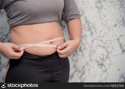 Woman touching stomach holding measuring tape ,Obese with fat belly in dieting concept. touching stomach holding measuring tape