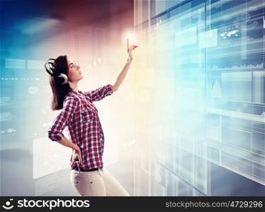 Woman touching virtual screen. Image of young woman with headphones touching virtual screen