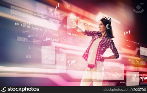 Woman touching virtual screen. Image of young woman with headphones touching virtual screen