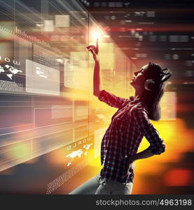 Woman touching virtual screen. Image of young woman with headphones touching virtual screen