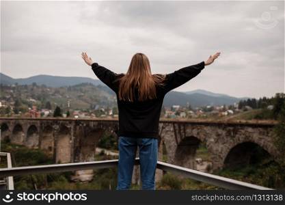 Woman tourist enjoys traveling to historical places in Ukraine, viaduct in the mountain resort village of Vorokhta, Carpathians. Travel concept. Woman tourist enjoys traveling to historical places in Ukraine, viaduct in the mountain resort village of Vorokhta, Carpathians. Travel concept.