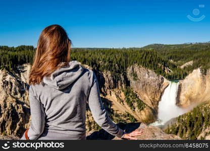 Woman tourist overlooking Lower Falls waterfall in the Grand Canyon of Yellowstone National Park, Wyoming, USA