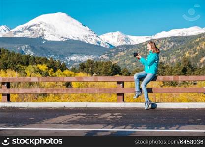 Woman tourist taking photo. Season changing from autumn to winter. Rocky Mountains, Colorado, USA.