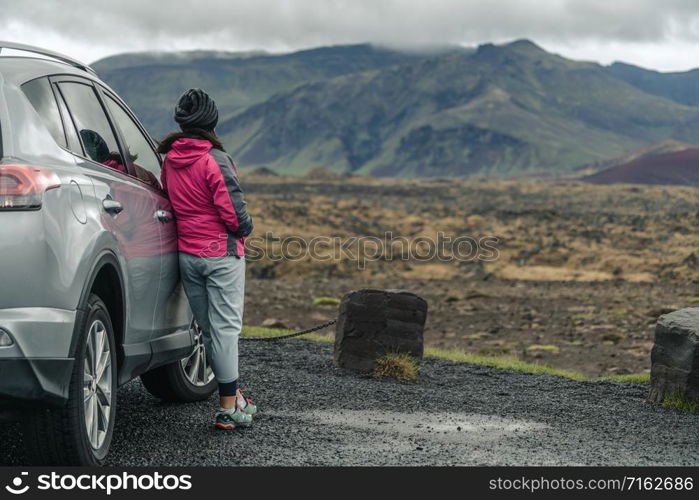 Woman tourist travel by SUV car for road trip in Iceland. The traveler parking the car and enjoy beautiful scenery of mountain landscape in the background. Discovery and exploration.