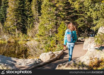 Woman tourist walking on trail near Bear Lake at autumn in Rocky Mountain National Park. Colorado, USA.