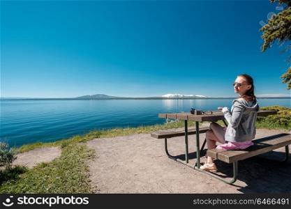 Woman tourist with camera having a breakfast by Yellowstone Lake, Wyoming, USA