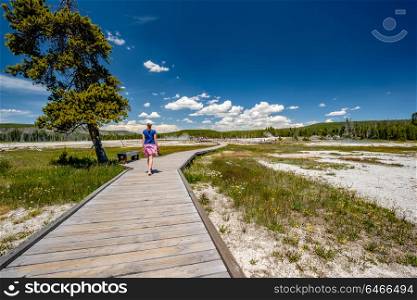 Woman tourist with camera hiking in Yellowstone National Park, Black Sand Basin area, Wyoming, USA