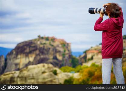 Woman tourist with professional camera taking picture film video from monastery. The Meteora monasteries, Greece Kalambaka.. Woman take photo from Meteora monastery