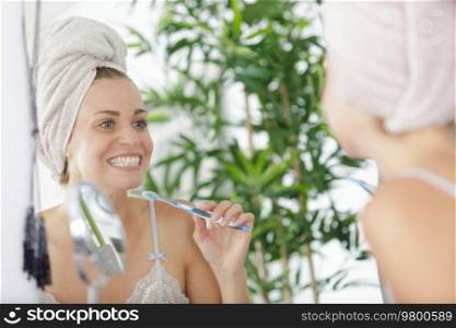 woman towelhead brushing her teeth