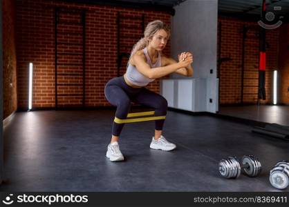 Woman training with fitness rubber band at gym sport club. Exercise workout for legs and booty pump. Woman training with fitness rubber band