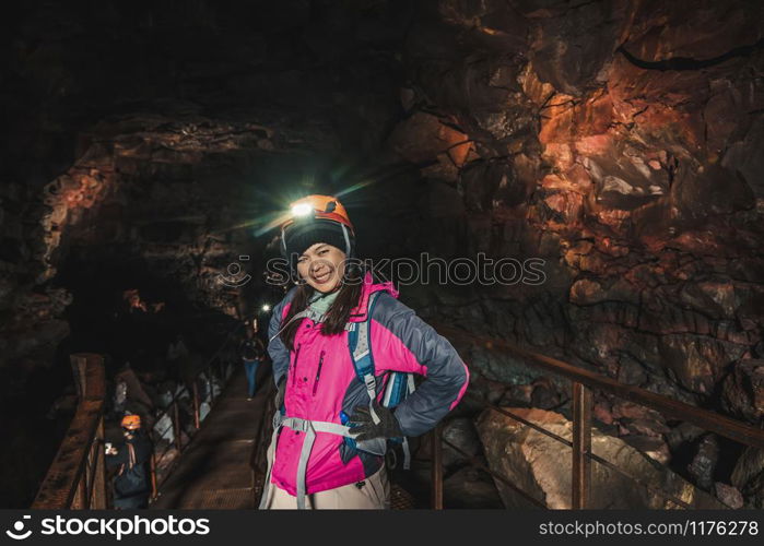 Woman traveler explore lava tunnel in Iceland. Raufarholshellir is a beautiful hidden world of cave. It is one of the longest and best-known lava tubes in Iceland, Europe for incredible adventure.