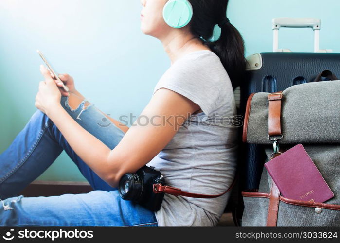 Woman traveler holding smart phone and listening to music with t. Woman traveler holding smart phone and listening to music with traveler suitcases behind, Happy and Travel lifestyle concept