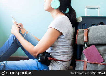 Woman traveler holding smart phone and listening to music with t. Woman traveler holding smart phone and listening to music with traveler suitcases behind, Happy and Travel lifestyle concept