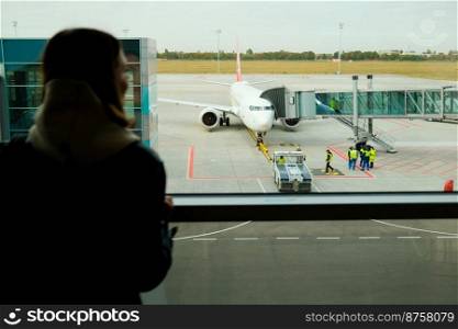 Woman traveler standing near panoramic big window at airport. Lady waiting for flight. Travel, journey, airplane concept. High quality photo. Woman traveler standing near panoramic big window at airport. Lady waiting for flight. Travel, journey, airplane concept.