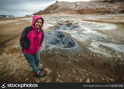 Woman traveler travels to Hverir in Iceland. Hverir (Icelandic: Hverarond) is geothermal area in Myvatn. It is a famous destination near Lake Myvatn, Krafla northeastern region of Iceland, Europe.