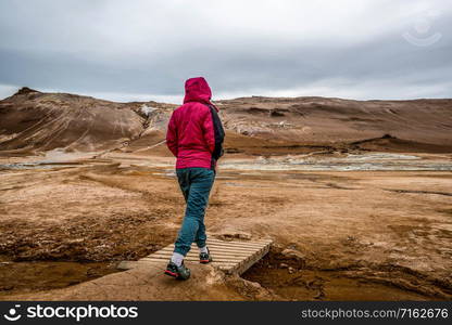 Woman traveler travels to Hverir in Iceland. Hverir (Icelandic: Hverarond) is geothermal area in Myvatn. It is a famous destination near Lake Myvatn, Krafla northeastern region of Iceland, Europe.