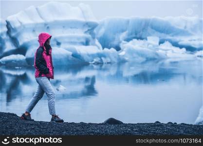 Woman traveler travels to Jokulsarlon beautiful glacial lagoon in Iceland. Jokulsarlon is a famous destination in Vatnajokull National Park, southeast Iceland, Europe. Cold winter ice nature.