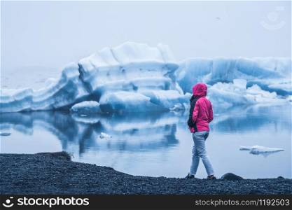 Woman traveler travels to Jokulsarlon beautiful glacial lagoon in Iceland. Jokulsarlon is a famous destination in Vatnajokull National Park, southeast Iceland, Europe. Cold winter ice nature.