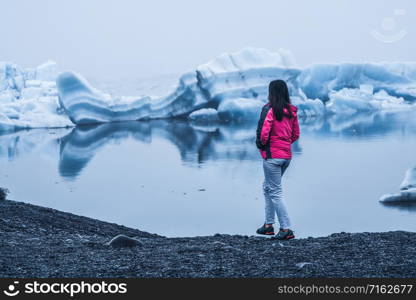 Woman traveler travels to Jokulsarlon beautiful glacial lagoon in Iceland. Jokulsarlon is a famous destination in Vatnajokull National Park, southeast Iceland, Europe. Cold winter ice nature.