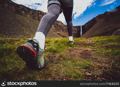 Woman traveler trekking in Icelandic summer landscape at the Hengifoss waterfall in Iceland. The waterfall is situated in the eastern part of Iceland.