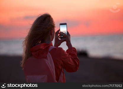 Woman traveler using smartphone and taking photo of colorful sea sunset.. Woman traveler using smartphone and taking photo of colorful sea sunset