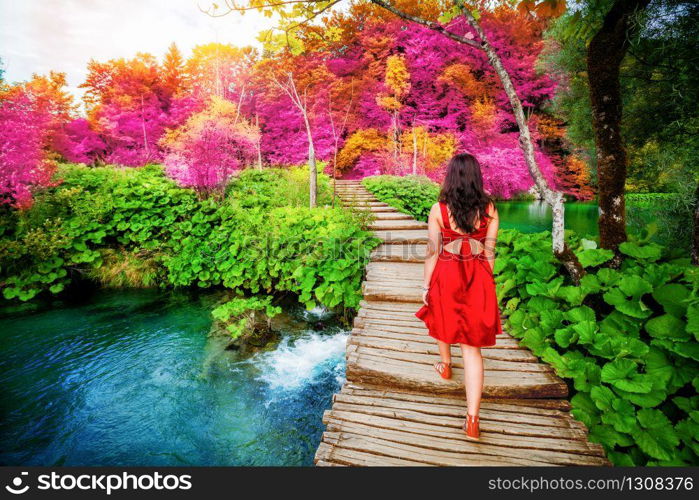 Woman traveler walking on wooden path trail with lakes and waterfall landscape in Plitvice Lakes National Park, UNESCO natural world heritage and famous travel destination of Croatia.. Traveler walk on path in Plitvice Lakes, Croatia.