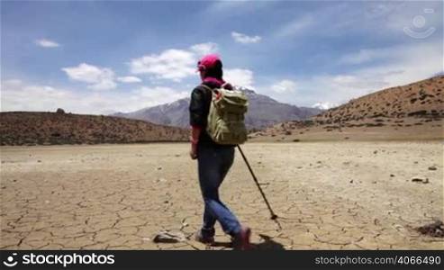 Woman traveler walks on a dry mountain lake. India.