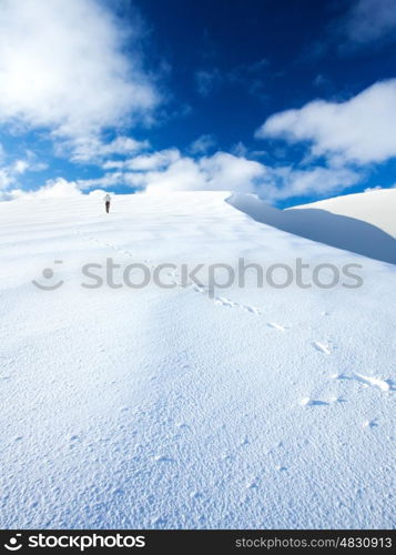 Woman traveling in the mountains in wintertime, active sportive lifestyle, walking along beautiful white snow, happy winter holidays