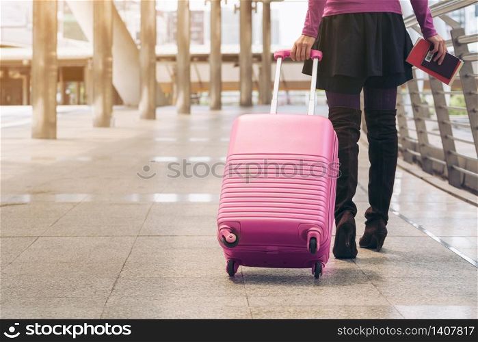 Woman traveller with travel bag or luggage walking in airport terminal walkway for travel abroad.