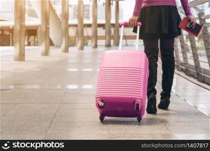 Woman traveller with travel bag or luggage walking in airport terminal walkway for travel abroad.