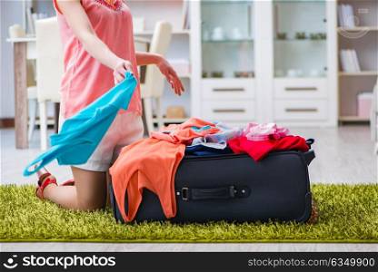 Woman trying to fit all clothing to suitacase before vacation