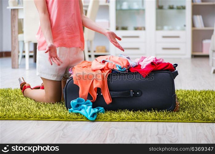 Woman trying to fit all clothing to suitacase before vacation