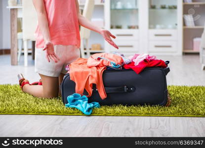 Woman trying to fit all clothing to suitacase before vacation