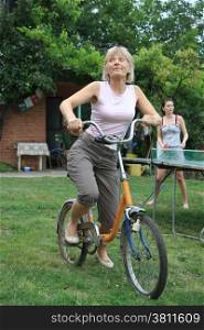 Woman trying to ride old bicycle