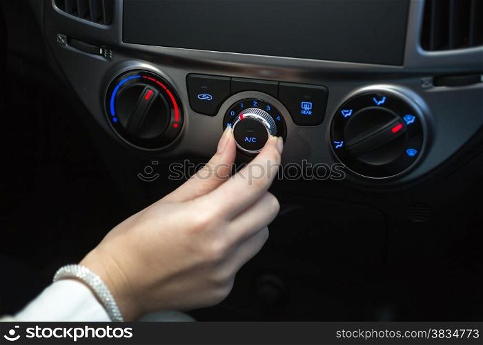 Woman turning on car air conditioning system
