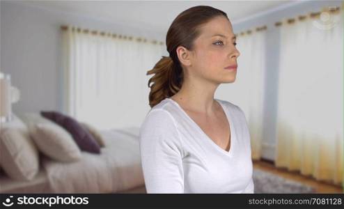 Woman turns and stares expressionless in bedroom