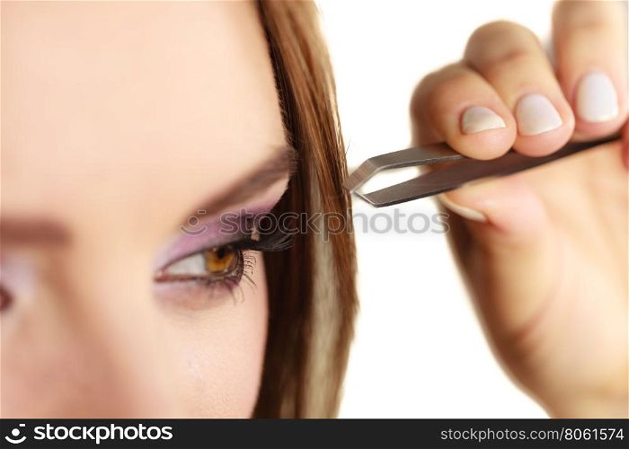 Woman tweezing eyebrows plucking with tweezers . Make up and cosmetics. Woman plucking eyebrows depilating with tweezers. Attractive girl tweezing eyebrows