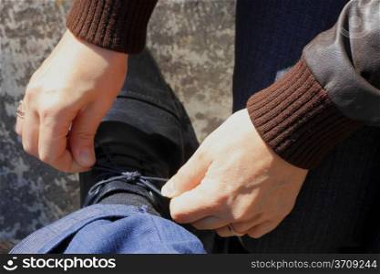 Woman tying a shoelaces on the mans shoes