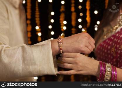 Woman tying rakhi on her brother&rsquo;s hand