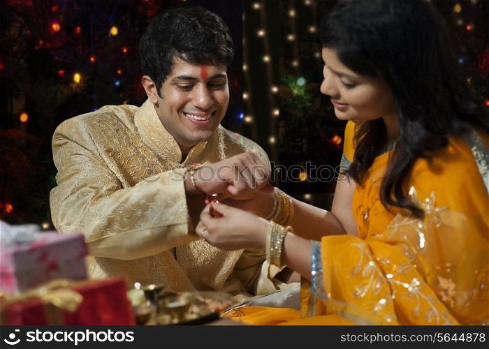 Woman tying rakhi on her brother&rsquo;s hand