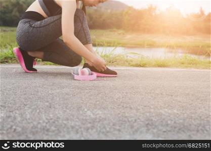 woman tying shoe laces. Female sport fitness runner getting ready for jogging outdoors on road in park